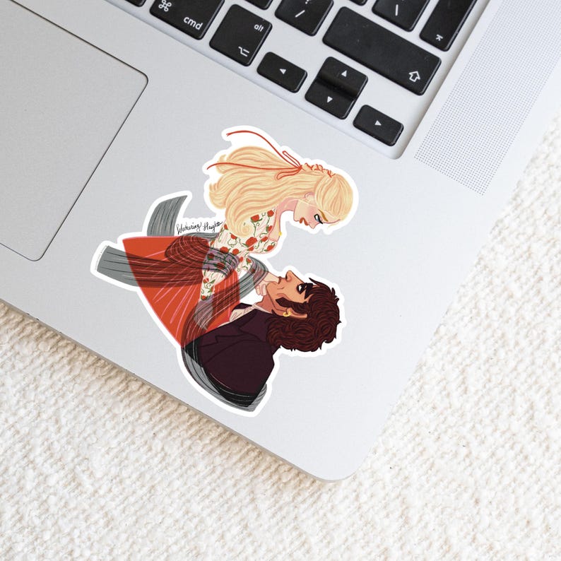 May include: A sticker featuring an illustration of a man and woman in a romantic embrace. The woman has long blonde hair and a floral dress. The man wears a dark suit. The sticker is on a laptop.