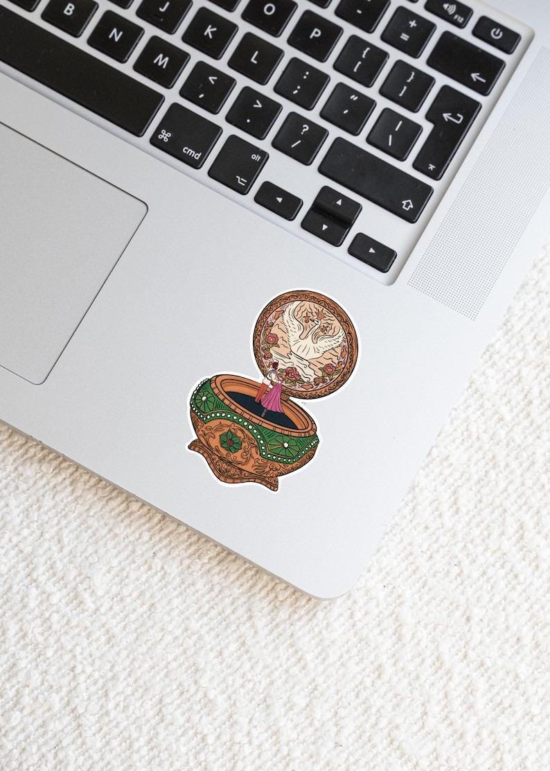 May include: A vintage-style music box with a ballerina inside. The music box is made of gold and green with intricate details. The lid is open and a white dove is flying out.