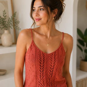 Peut inclure: Un débardeur en tricot sans manches de couleur terre cuite avec une encolure en V, de fines bretelles et un motif en dentelle tricotée verticale sur le panneau central, complété par un délicat motif ajouré sur les panneaux latéraux.