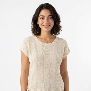 Peut inclure: Un haut en tricot de couleur crème à manches courtes, doté d'une encolure ronde et d'une texture côtelée verticale. Le vêtement est confectionné dans un tissu tricoté léger et respirant qui présente un motif constant de lignes verticales.