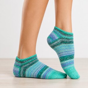 Peut inclure: Une paire de socquettes présentant un motif en tricot varié dans des tons de sarcelle, turquoise, bleu clair et vert foncé. Les chaussettes ont un bord-côte à la cheville ainsi qu'un talon et une pointe renforcés avec une finition en fil texturé.