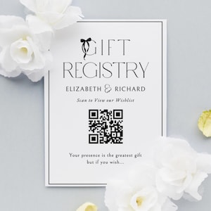 Puede incluir: Una tarjeta blanca de registro de regalos con texto negro, con las palabras "GIFT REGISTRY" y los nombres "ELIZABETH & RICHARD". Incluye un código QR y el texto "Scan to View our Wishlist". Flores blancas están dispuestas alrededor de la tarjeta.
