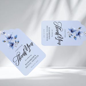 May include: Two light blue gift tags with a floral design and the words "Thank You" in elegant script. The tags are for Elizabeth's Bridal Shower, with the date March 12, 2020. The tags are attached to a white string.