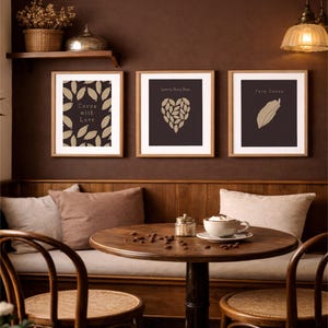 Peut inclure: Trois impressions d'art encadrées avec des motifs sur le thème du cacao sont accrochées à un mur marron. Les impressions présentent des feuilles de cacao, une forme de cœur faite de feuilles et une seule gousse de cacao. Le texte "Cocoa with Love", "Love in Every Bean" et "Pure Cocoa" est affiché.