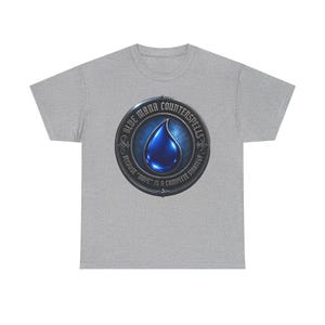 Peut inclure: Un t-shirt gris chiné à manches courtes avec un motif circulaire sur la poitrine. Le design présente une icône de goutte d'eau bleue centrale entourée d'une bordure métallique avec le texte "BLUE MANA COUNTERSPELLS" et "BECAUSE "NOPE" IS A COMPLETE STRATEGY".