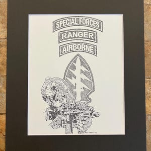 May include: Black and white print of a soldier with a rifle, the words "SPECIAL FORCES", "RANGER", and "AIRBORNE" are above a Special Forces insignia. The print is on white paper, matted in black, and framed.