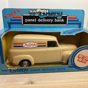 May include: A die-cast metal 1948 Chevy panel delivery bank in a box. The beige truck has the True Value logo on the side. The blue box has the text "48 Chevy panel delivery bank" and "DIE-CAST METAL".