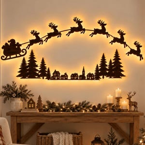 Può includere: Un'opera d'arte da parete in metallo marrone scuro che raffigura la sagoma di Babbo Natale su una slitta trainata da sei renne che volano sopra un villaggio con alberi di pino. Il design è retroilluminato da una calda luce gialla.