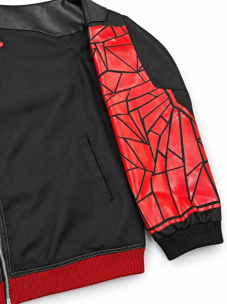 May include: Black jacket with a red geometric design on the right sleeve. The jacket has a black collar, a red ribbed hem, and a zipper closure. The sleeve design features red shapes outlined in black.