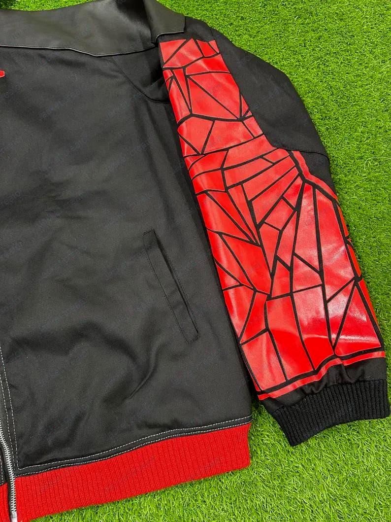 May include: Black jacket with a red geometric design on the right sleeve. The jacket has a black collar and a red ribbed hem and cuffs. A silver zipper runs down the front.