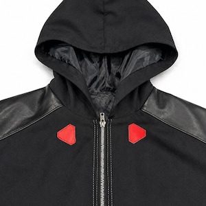 May include: Black hooded jacket with a full-length zipper and red accents. The jacket features black faux leather shoulder panels and a black hood with a satin lining. The hood is attached to the jacket's collar.