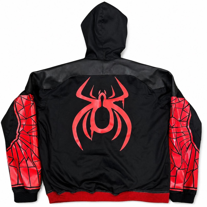 May include: Black hooded jacket with a red spider emblem on the back. The jacket features red and black geometric designs on the sleeves, a black hood, and a red trim at the bottom. The jacket has a black leather-like panel across the shoulders.