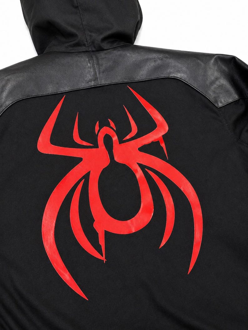 May include: Black hooded jacket with a red spider graphic on the back. The jacket features a black leather panel across the shoulders and hood. The spider design is a bold, stylized illustration.