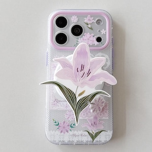 May include: A clear smartphone case with a white grid pattern, featuring a large light purple lily flower attachment in the center. The case has a light purple camera frame and includes printed floral designs and the text Romantic and Sysa Case.