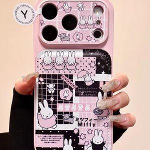 May include: Pink phone case with a cartoon bunny design and Japanese text. The case has a two-tone design with a pink top section and a patterned bottom section with bunny illustrations and stars.