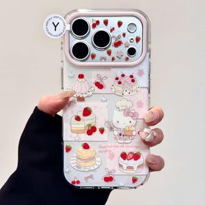 May include: Clear phone case with a pink border featuring a design of cakes, strawberries, and a cartoon cat. The case has a clear back and a pink camera border. The text "Sweet heart kitty with strawberry and cherry" is visible.