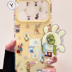 以下が含まれることがあります： スポンジ・ボブのキャラクターが描かれた、黄色い色味の透明なスマートフォンケース。小さなキャラクターのイラストと、大きな手形のグリップが付いています。ケースには黄色のカメラフレームとY2CASEのロゴステッカーが貼られています。