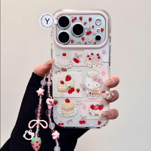 May include: Clear phone case with a pink border featuring a collage of strawberry and cake illustrations. A pink and clear beaded wrist strap with star and bow charms is attached. The case has a Hello Kitty theme.