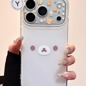 Op de afbeelding: Transparante telefoonhoes met een wit stippenpatroon en een cartoon berengezichtontwerp. De hoes heeft een transparante cameralensbeschermer met kleine cartoonkarakterstickers. Het Y2CASE-logo is zichtbaar op een ronde sticker.