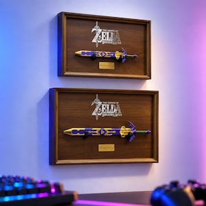 May include: Two rectangular wooden wall displays featuring The Legend of Zelda: Breath of the Wild logo in silver. Each frame holds a replica Master Sword with a purple and gold scabbard and a gold-toned hilt, accompanied by a small Master Sword label.