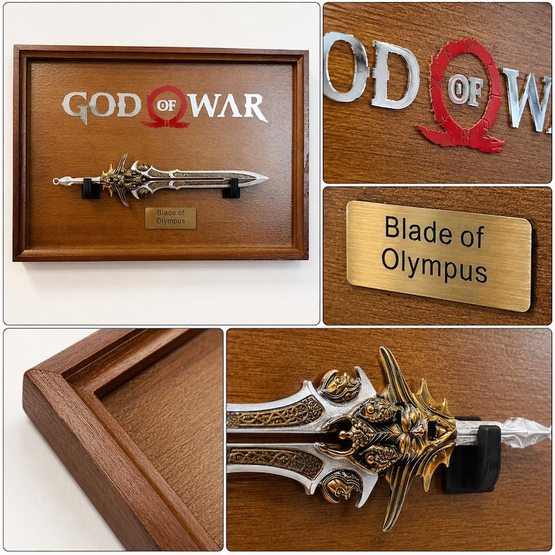May include: A framed display featuring a replica of the "Blade of Olympus" from the "God of War" video game. The sword is silver and gold, mounted on a wooden plaque with the game's logo and a nameplate.