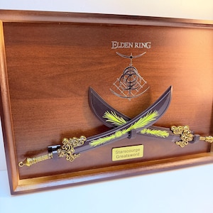 May include: A wooden framed display with two crossed swords, each with gold handles and yellow detailing on the blades. The text "Elden Ring" is above the swords, and a plaque reads "Starscourge Greatsword."