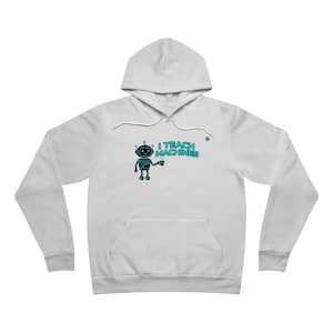 Puede incluir: Sudadera con capucha blanca con bolsillo delantero y cordón. El diseño presenta un robot de dibujos animados sosteniendo una taza, con el texto "I TEACH MACHINES" en color turquesa.