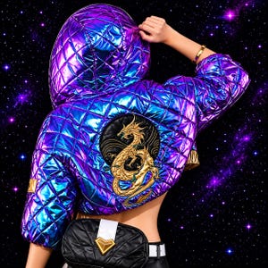 May include: A quilted, iridescent purple and blue jacket with a hood. The jacket features a gold dragon emblem on the back. A black fanny pack with a gold accent is worn at the waist. The background is a starry night sky.