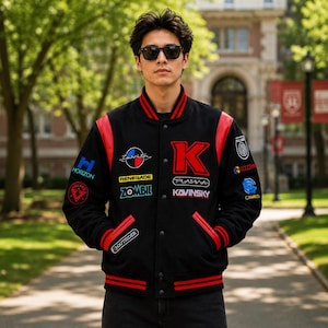 May include: Black varsity jacket with red accents on the shoulders, sleeves, and collar. The jacket features various patches with text including "Horizon", "Renegade", "Zombie", "Kavinsky", and a large red "K" on the chest. The jacket has a button-up front.