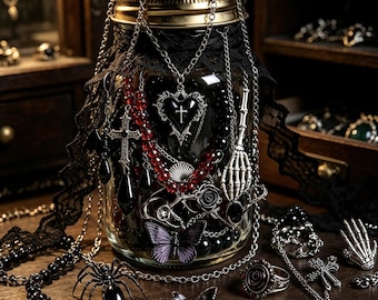 May include: A clear glass jar with a gold lid, wrapped in black lace, containing various silver-toned necklaces with heart, cross, and skeleton hand charms, red beads, and a purple butterfly. Several rings and a spider figurine sit nearby.