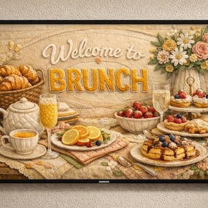 Puede incluir: Una obra de arte enmarcada con temática de brunch. La imagen presenta una mesa llena de comida, incluyendo cruasanes, gofres, fruta y pasteles. Las palabras "Welcome to BRUNCH" se muestran de forma destacada. También se ve un jarrón de flores y una taza de café.