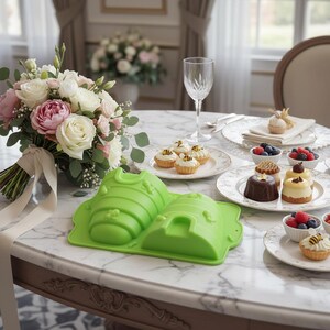 Può includere: Uno stampo in silicone verde a forma di alveare e ape, con un bouquet di rose bianche e rosa, e piccoli dessert su un tavolo di marmo. I dessert includono crostatine con decorazioni di api e piccole torte con frutti di bosco.