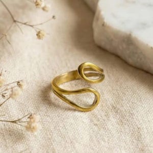 Könnte beinhalten: Ein Set aus drei Keramikbechern mit gesprenkelter, matter Oberfläche. Die Becher sind in Creme-, Hellgrau- und Dunkelgrautönen gehalten. Jeder Becher hat ein schlichtes, minimalistisches Design und einen abgerundeten Henkel.