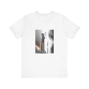 May include: White t-shirt featuring a graphic of a rocket on a launch pad with a moon in the background. The rocket is orange and gray. The text "ROCK + ROLL" is printed vertically on the left side of the rocket.
