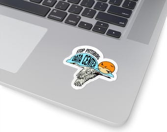 May include: A die-cut sticker featuring a white crane in flight against a light blue cloud shape and an orange sun. The text STOP PITTSBURG DATA CENTER is printed in black capital letters along the top edge of the blue cloud graphic.