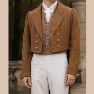 May include: A tan tailcoat jacket with gold buttons, a brown textured vest, a white collared shirt with a white cravat, and white trousers. The ensemble features a structured silhouette with long coat tails and a formal layered appearance.