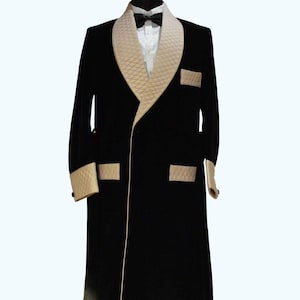 May include: A black velvet smoking jacket with a cream-colored quilted shawl collar, cuffs, and pocket accents. The jacket features a satin trim and tassel details, creating a luxurious and elegant look. A black bow tie and white dress shirt are visible.