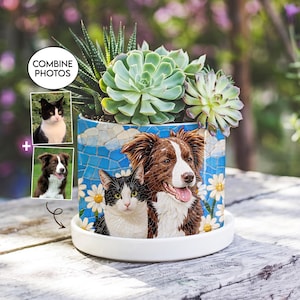 May include: A cylindrical ceramic planter featuring a mosaic-style illustration of a black and white cat and a brown and white dog surrounded by white daisies against a blue background. The planter holds green succulents and sits on a white saucer.