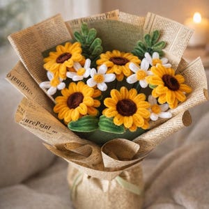 May include: A bouquet of handmade sunflowers and daisies wrapped in vintage newspaper. The sunflowers have bright yellow petals and brown centers, while the daisies are white with yellow centers. The bouquet is tied with a green ribbon.