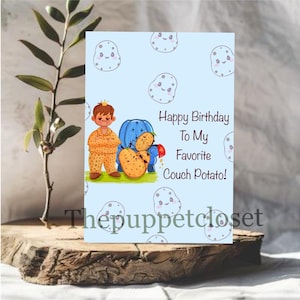 Puede incluir: Tarjeta de cumpleaños azul claro con el texto "Happy Birthday To My Favorite Couch Potato!". Presenta una ilustración de dibujos animados de una persona en pijama y patatas. La tarjeta tiene un fondo azul claro con diseños de patatas.