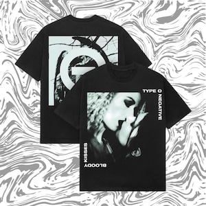 May include: Two black t-shirts with white graphics. One features a tree branch design with a large letter "O". The other displays a black and white image of a couple kissing, with the words "TYPE O NEGATIVE" and "BLOODY KISSES".