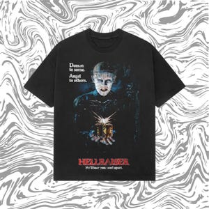Może przedstawiać: Czarny t-shirt z grafiką z filmu Hellraiser. Projekt zawiera tekst "Demon to some. Angel to others." i "HELLRAISER He'll tear your son! apart."