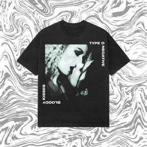 May include: Black t-shirt featuring a grayscale image of two people kissing. The text "TYPE O NEGATIVE" is printed vertically on the right side, and "BLOODY KISSES" is printed vertically on the left side of the image.