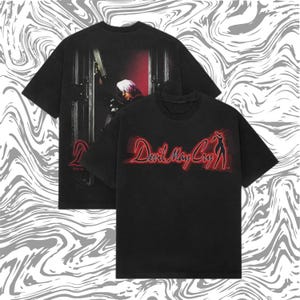 Könnte beinhalten: Schwarze T-Shirts mit dem "Devil May Cry"-Logo in Rot und einer Charakter-Silhouette. Die Rückseite eines Shirts zeigt einen Charakter mit einer Waffe. Die Shirts haben einen Vintage-Look.