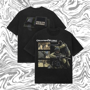 May include: Two black t-shirts with Counter-Strike: Source graphics. One shows a keypad, the other a scene with soldiers and the game logo. The shirts have a vintage, worn appearance. The background has a swirling pattern.