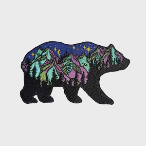 May include: Embroidered patch featuring a black bear silhouette with a mountain and starry night design. The mountains are in shades of purple, green, and blue, with yellow stars against a dark blue sky. This patch is suitable for jackets, bags, or other fabric items.