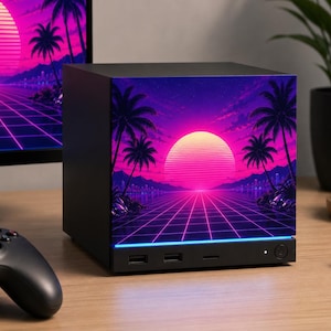 May include: A black square computer case featuring a vibrant front panel graphic of a glowing pink sun setting over a grid landscape with palm trees. The base of the front panel includes two USB ports, a small indicator light, and a circular power button.