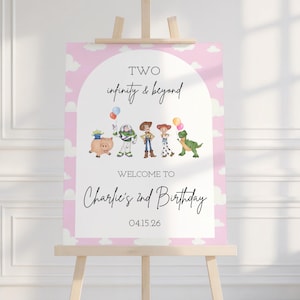 May include: A pink and white welcome sign on a wooden easel. The sign features the phrase "Two infinity & beyond" and "Welcome to Charlie's 2nd Birthday" with cartoon characters and balloons. The date 04.15.26 is also included.