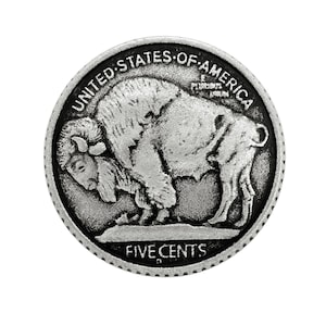 Puede incluir: Una moneda circular de tono plateado con un relieve de un bisonte americano de pie sobre un montículo. El texto UNITED STATES OF AMERICA está arqueado en la parte superior, E PLURIBUS UNUM a la derecha y FIVE CENTS en el borde inferior.