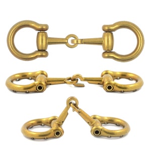 Puede incluir: Tres bocados de caballo de metal dorado. El bocado superior tiene un anillo en D en cada extremo. El bocado del medio tiene un anillo en D en cada extremo y un pequeño anillo de conexión en el centro. El bocado inferior tiene dos anillos en D en cada extremo y un anillo de conexión en el centro.